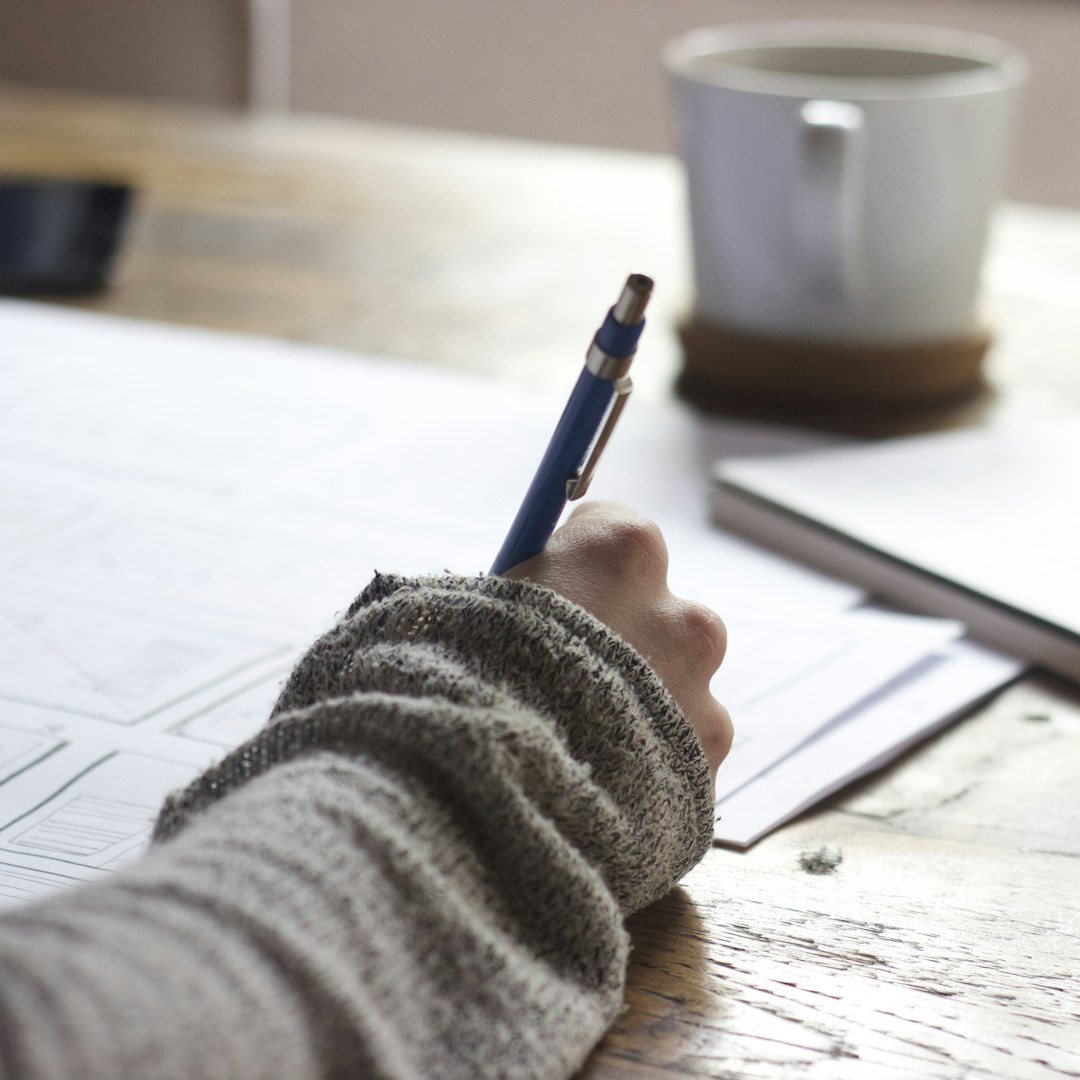 A student writing out an answer by hand at a desk